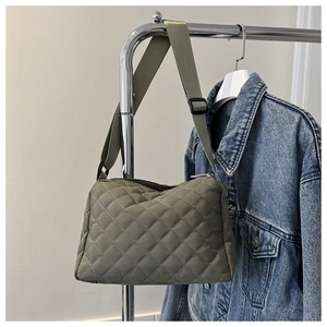 Detail of olive green quilted crossbody bag with diamond patterns and adjustable strap