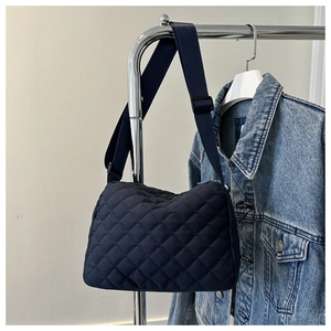 Close-up of dark blue quilted crossbody bag with adjustable strap and diamond texture