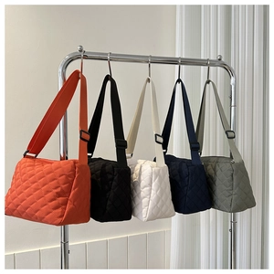 Close-up of five colorful quilted crossbody bags with wide fabric straps on display