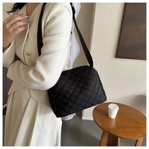 Detail view of quilted puffer shoulder bag in black with adjustable wide strap