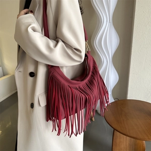 Chic burgundy crescent tassel shoulder bag styled with a beige trench coat for autumn fashion