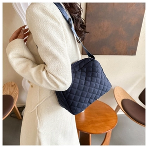 Close-up of quilted pattern on dark blue nylon shoulder bag with zipper and wide strap
