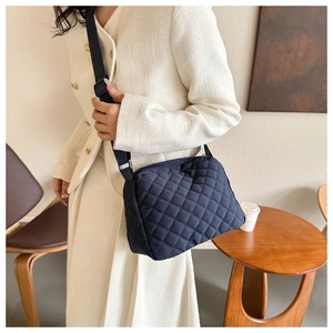 Close-up of quilted navy crossbody bag with adjustable wide strap on model