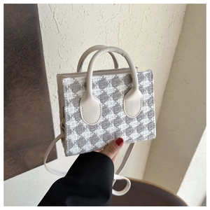 Detailed view of mini houndstooth plaid handbag with circular handles and shoulder strap