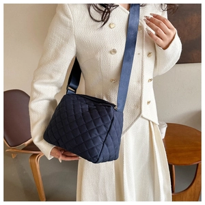Detailed view of navy blue quilted crossbody bag with stylish diamond pattern and wide strap