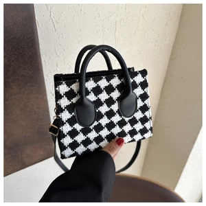 Detailed close-up of a small houndstooth plaid handbag with gold metal buckles