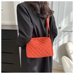 Detail of vibrant orange quilted crossbody bag featuring a rhombus pattern nylon texture