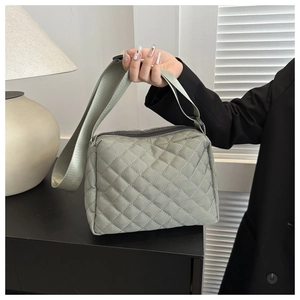 Detail of sage green quilted crossbody bag featuring soft padded nylon and wide strap