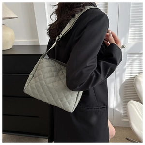 Detailed side view of sage green quilted crossbody bag on female model in casual attire