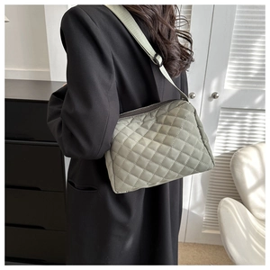 Close-up of light green quilted shoulder bag with diamond pattern and wide strap