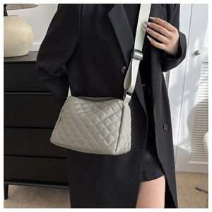 Detailed view of light green quilted shoulder bag with matching wide fabric strap
