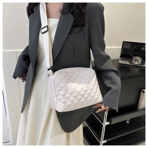 Detail of white quilted nylon crossbody bag featuring a wide adjustable woven strap