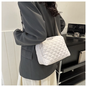 Close-up of white quilted puffer shoulder bag styled with a professional office outfit