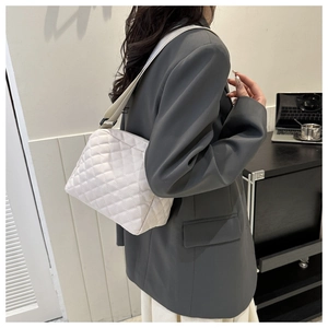 Lifestyle shot of a white quilted crossbody bag with wide shoulder strap on a female model