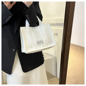 Close-up of white quilted nylon tote bag with vertical stripes and fashion label