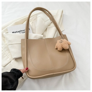 Detail of khaki PU leather tote bag with U-shaped stitching and bear charm