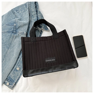 Close-up of black quilted tote bag with Fashion Bag label and durable leather bottom
