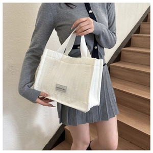 Close-up of a white quilted tote bag featuring a wave pattern and fashion bag label