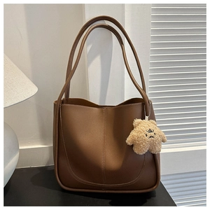 Detailed view of deep brown PU leather tote bag with a cute beige plush bear pendant