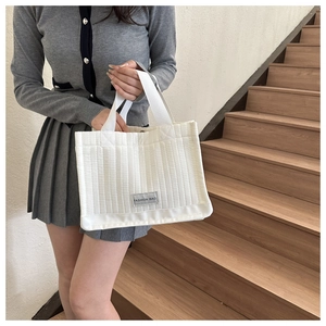 Close-up of white quilted tote bag with vertical stripes and FASHION BAG label