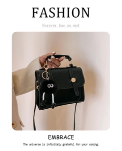 Détail du sac bandoulière noir avec boucle dorée et pendentif monstre en peluche