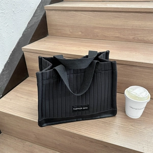 Fashionable black quilted tote bag with vertical stripes on a stylish wooden staircase