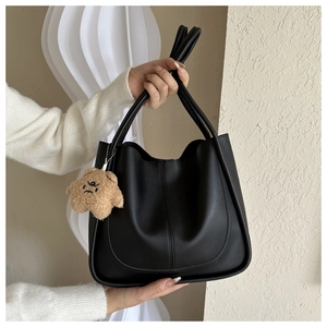 Detail of black PU leather tote bag with a cute star plush pendant in a stylish pose