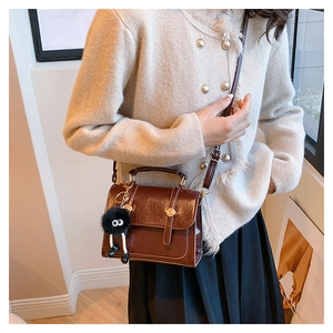 Dettaglio borsa a tracolla in pelle vintage marrone con ciondolo a peluche nero carino
