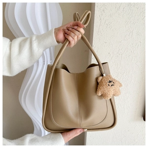Detail of minimalist beige PU leather handbag with cute plush animal charm accessory