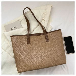 Détail macro du cuir tressé kaki sur un grand sac à main cabas pour femme