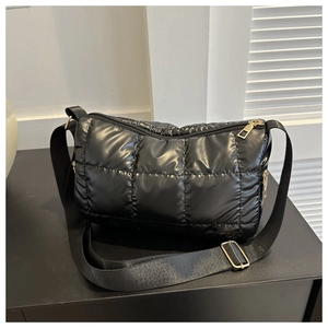 Vue détaillée du sac matelassé noir en nylon brillant avec des détails de fermeture éclair dorés