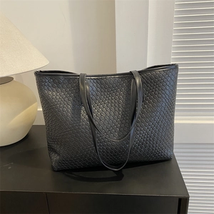 Grand sac cabas noir en cuir tressé avec doubles anses dans un décor intérieur
