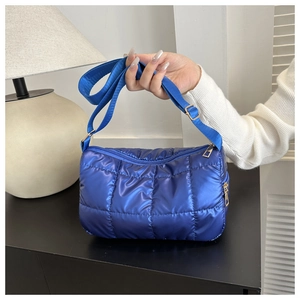 Détail du sac matelassé en nylon bleu avec fermeture dorée et bandoulière réglable