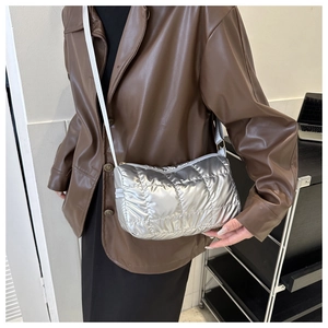 Detail of silver quilted puffer crossbody bag showing metallic fabric and zipper closure