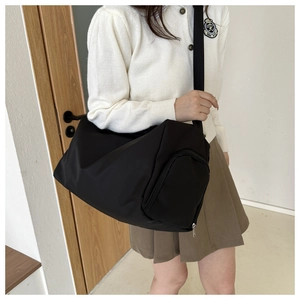 Modische schwarze Nylon Sporttasche am Modell in einem lässigen Innenraum