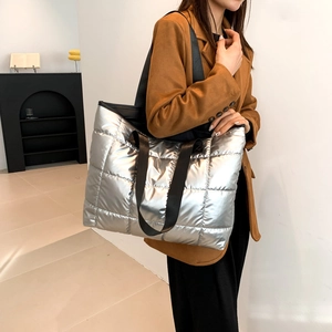 Silver quilted oversized tote bag with metal finish and wide black shoulder straps
