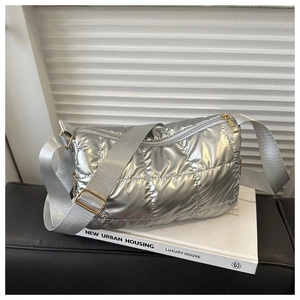 Detail of silver quilted puffer bag featuring metallic finish and wide nylon strap
