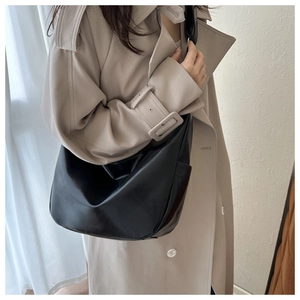 Minimalist black oversized hobo bag on a model wearing a classic beige trench coat