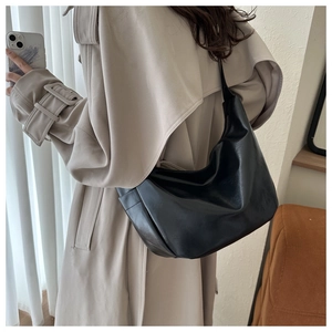 Detail of a black PU leather hobo bag showing soft texture and shoulder strap on model
