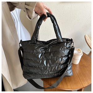 Detail of black puffer tote bag with quilted nylon texture and adjustable shoulder strap