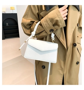 Dettaglio borsa bianca in pelle con manico intrecciato e anelli metallici oro
