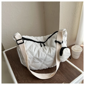 Detailed shot of white quilted padded crossbody bag with mini pouch on wooden desk