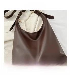 Detail view of large dark brown PU leather tote bag with gold metal rings and zipper