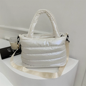 White puffer tote bag with quilted texture and adjustable crossbody strap on white surface
