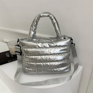 Silver quilted padded tote bag with metallic finish and wide shoulder strap shown on podium