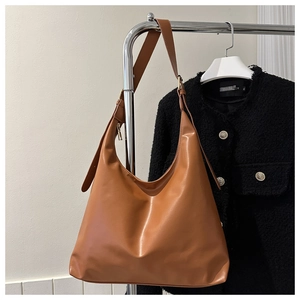 Detail of adjustable wide shoulder strap and gold hardware on tan faux leather tote bag
