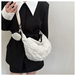 Close-up of a white quilted crescent bag featuring a matching round coin purse on the strap