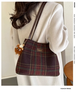 Detail of wool bucket tote bag with purple plaid pattern and leather handles shown on model