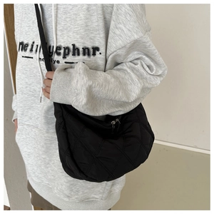 Detailed view of the black quilted crossbody bag with moon shape and zip closure
