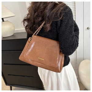 Détail du sac cabas marron vintage avec bandoulière chaîne et lettrage de la marque